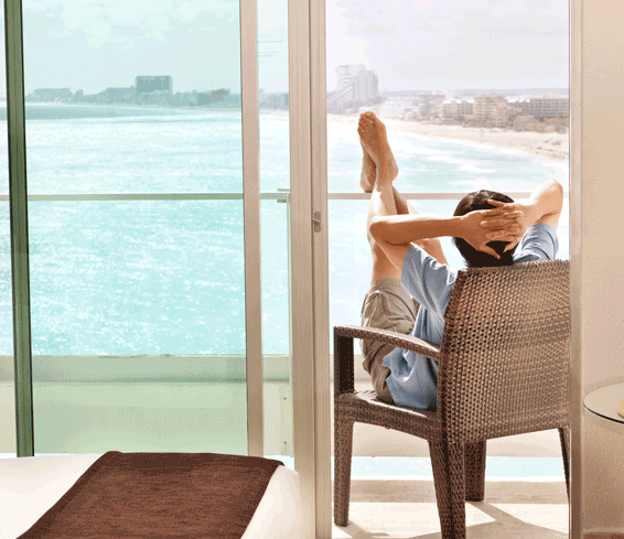 Man on vacation relaxing in hotel room balcony with a view